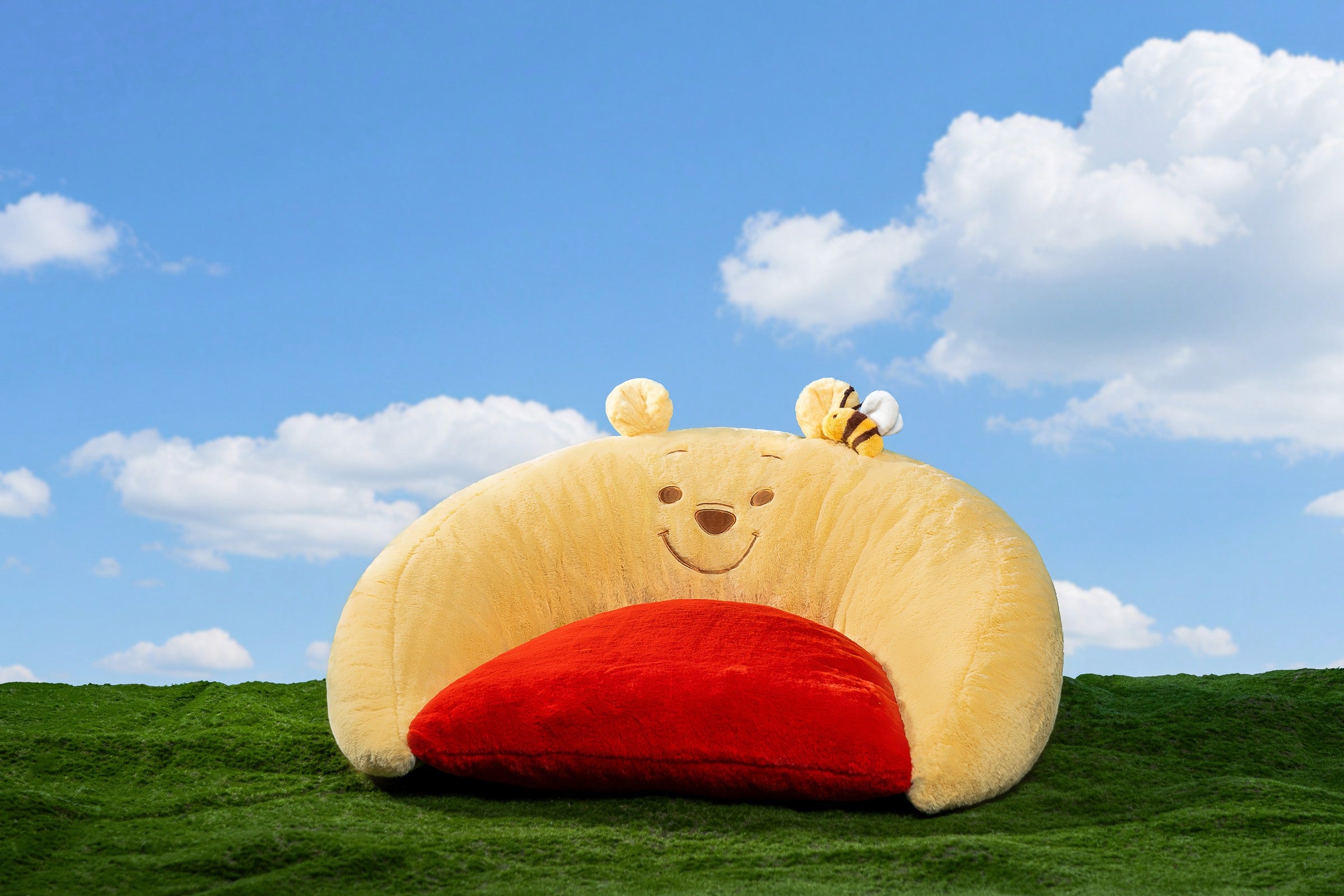 Yellow Winnie the Pooh sofa bed with a red seat and bee detail on a green and blue garden set